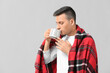 © Pixel-Shot - Handsome young man with cup of tea on grey background