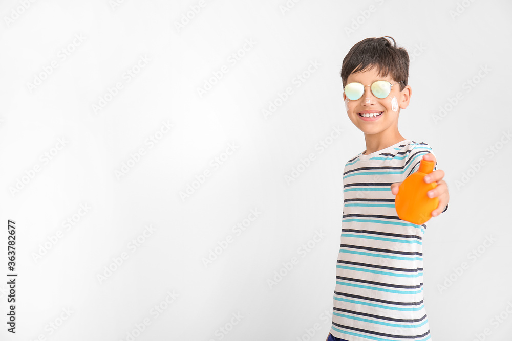 Little boy with sun protection cream on grey background