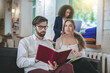 © zinkevych - Bearded guy reading book and two girls.