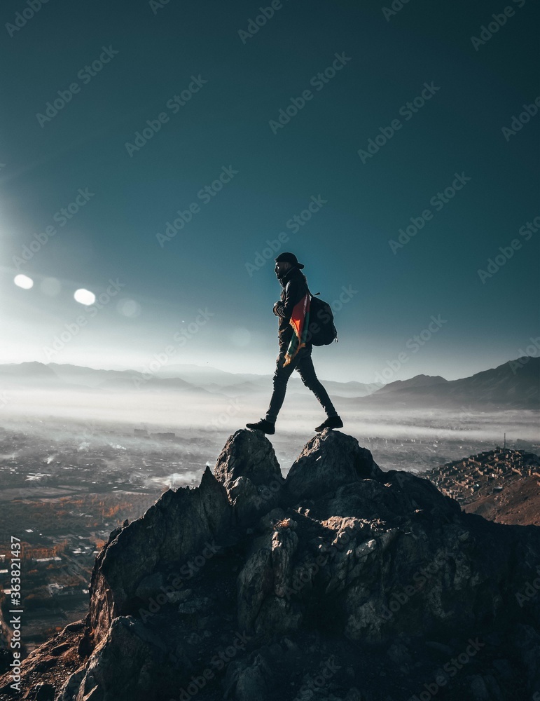 Man Standing On Rocky Mountain Against Sky - obrazy, fototapety, plakaty 