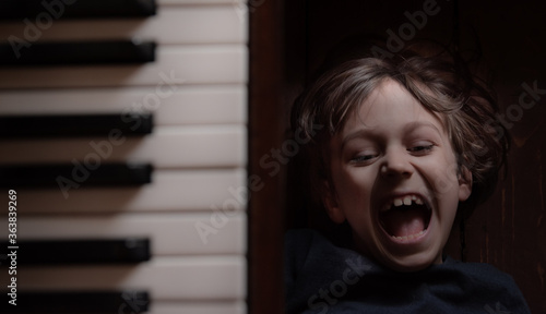 Portrait Of A Laughing Kid Laying On The Floor Near Piano