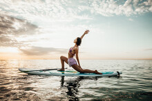 Young Woman Doing YOGA On A SUP Board In The Lake At Sunrise