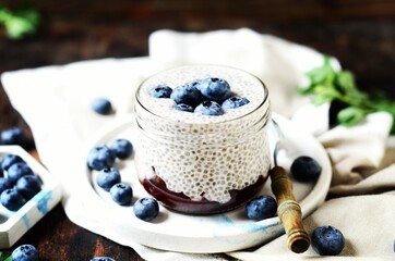 Wall Mural - Chia pudding with jam and blueberries in glass jars on a dark wooden background, still life