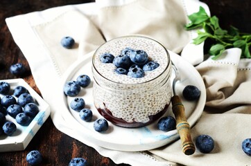 Wall Mural - Chia pudding with jam and blueberries in glass jars on a dark wooden background, still life