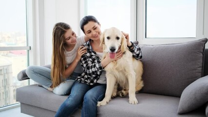 Canvas Print - Happy daughter and mother with adorable dog on sofa in modern apartment