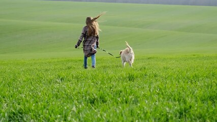 Canvas Print - Rear view of girl walking with dog on green field