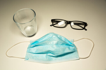 Surgical mask lying on the counter, glasses and an empty glass