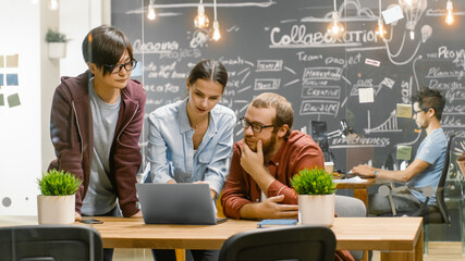 Wall Mural - three creative people have active discussion about ongoing project while using laptop. stylish young