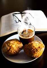 Poster - Vertical shot of a cup of coffee, muffins and an opened book