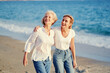 © luengo_ua - Outdoor portrait of smiling happy caucasian senior mother with her adult daughter hugging and walking on sea beach.