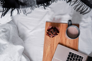 Wall Mural - Breakfast in bed: a wooden tray with muffin and cup of cocoa and laptop computer.