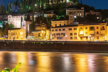 Wall Mural - Night photo along the Adige river overlooking the Roman theater and San Pietro castle, city of Verona, Italy.