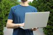 © Atlas - Young man in t-shirt holding laptop outdoor. Study. University