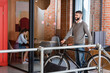 © LIGHTFIELD STUDIOS - selective focus of cheerful businessman standing with bicycle near businesswoman sitting in office