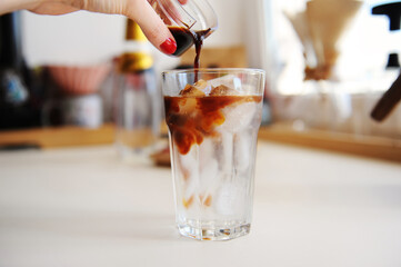 Wall Mural - Making espresso tonic. Pouring espresso into glass with tonic and ice