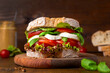 © Светлана Монякова - Big tasty sandwich of ciabatta with mozzarella cheese, tomatoes, basil and lettuce on the table. Sandwich with cheese and vegetables on a dark background, vegetarian food. Italian Cuisine.