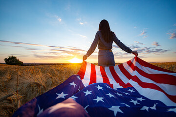 Wall Mural - Patriot girl with the flag of America at the wheat field against the sunset