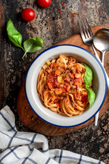 Pasta Bolognese. Tagliatelle with homemade bolognese sauce of minced meat, tomatoes, celery, carrots and spices in a bowl on a black background, top view. Italian Cuisine. 