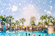 Foam pool party, bubbles blower and pool with people swimmng, dancing, relaxing and having fun against palms background. Summer holidays, fun sports, family travel, tourism.