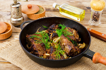 Wall Mural - Cast-iron frying pan on wooden table with fried liver.