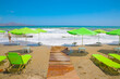 Crete beach Kalyves. Green umbrellas and sunbeds against the backdrop of a beautiful blue sea on a sunny day. Public beach Kalyves in Crete Island in Greece
