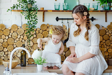 Small child girl playing in the kitchen at the table. Happy family mother and child, daughter prepare food at home. Raising a child in the game.