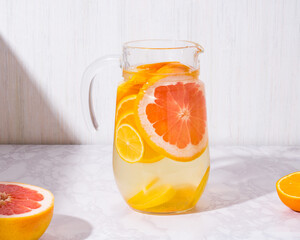 Lemonade with lemons and grapefruit in glass jar on white background. Cold summer refreshing drink or beverage