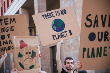 Group of young people at a demonstration for the environment - Young millennials protest at a procession to save the planet with slogans and drawn in the sign - Concept of manifestation