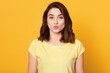 © sementsova321 - Portrait of lovely brunette female rounds lips as going to get kiss from boyfriend, looks at camera with pleased expression, isolated over yellow background.