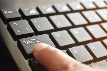 finger pressing tab button on keyboard.