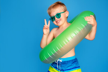 Happy cute baby boy 6-7 years old in sunglasses and with a life buoy. Summer and the sea.