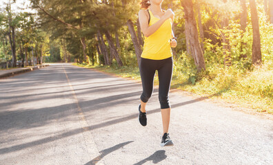 Wall Mural - Young fitness sport woman running on the road in the morning, Young fitness sportswoman runner running on tropical park trail. People and sport concept
