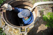 Worker cleans the sewer hatch.A worker cleans a sewer hatch. A man in the hatch.