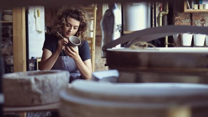 Wall Mural - Young woman decorating bowl made of clay on ceramics workshop
