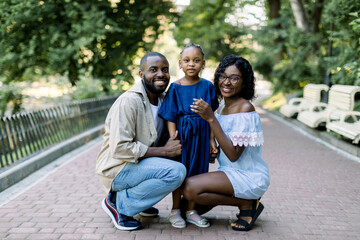 summer family portrait in nature outdoors. beautiful young african american family with cute little 