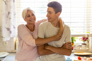 Mother hugging her teenage son in the kitchen
