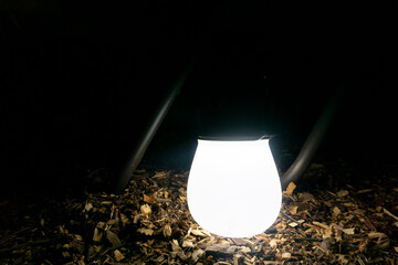 white plastic modern lantern glowing in the dark and standing on the ground