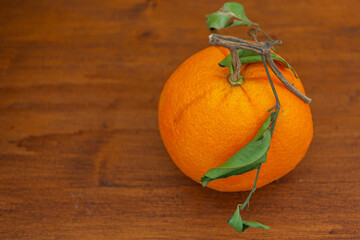 Orange with crumpled leaves on wooden blurred background. Space for text