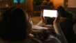 © Gorodenkoff - Evening at Home: Young Woman Resting on Couch using with White Mock-up Screen Smartphone. Girl Using Chroma Key Mobile Phone in Landscape Horizontal Mode, Internet Browsing, Posting on Social Networks