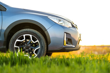 Close up of blue off road car on green grass. Traveling by auto, adventure in wildlife, expedition or extreme travel on a SUV automobile. Offroad 4x4 vehicle in field at sunrise.