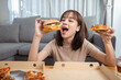Close up asian woman takeaway eating junk food hamburger and pizza.