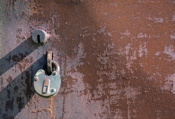 
Rusty metal door with peeling paint and an old lock.