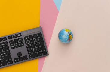 Global web. PC keyboard with globe on colored background. Top view