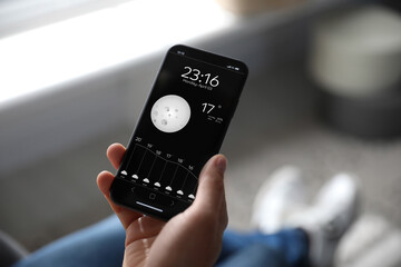 Wall Mural - man using weather forecast app on smartphone indoors, closeup