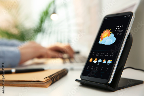 Fotografía Smartphone with open weather forecast app on white table indoors