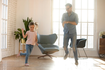 Canvas Print - Happy father and adorable little daughter dancing in modern living room, spending free leisure time together at home, celebrating moving day, smiling dad and cute preschool girl enjoying activity