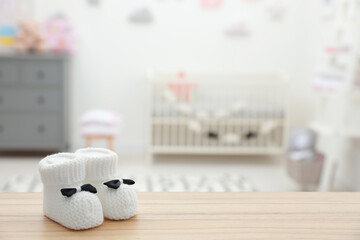Poster - Small baby booties on wooden table in room. Space for text