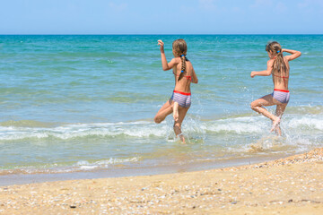 Two sisters run into the sea on a hot sunny day