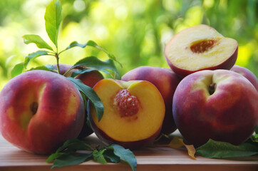 Fresh organic peaches, whole and sliced, with leaves, on table