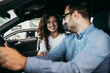 © Dusko - Happy middle age couple enjoying while choosing and buying new car at showroom.